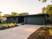A ranch house with a matte charcoal two-car garage door matching the dark siding and window trim