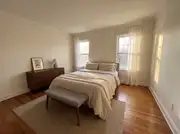 Small master bedroom with the bed centered between two windows and a bench at its foot