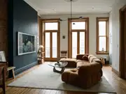 Living room with a dark charcoal accent wall behind framed art, a brown sectional, a glass coffee table, and tall windows