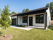 Cream single-story ranch with one black trim color on windows, fascia, porch posts, garage door and gutters