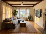A gray sectional sofa facing a wall-mounted TV across a wood coffee table centered on a jute rug