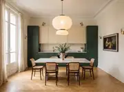 Full room view of a French Modern kitchen with two-tone green and beige cabinetry, herringbone parquet, and brass details.