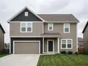 Two-story house with greige lap siding and charcoal board-and-batten only on the gable and garage band