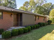 A brick ranch home entry with a vertical board-and-batten accent panel flanking the front door