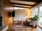 A wall-mounted TV on a tilting mount above a round coffee table with no console beneath it