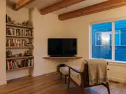 A TV angled on a slim floating shelf in a room corner, flanked by open shelving instead of a bulky cabinet