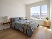 Small bedroom with a floating wood nightstand shelf and a slim two-drawer table beside the bed