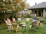 Mismatched wooden chairs, stools and folding chairs with patchwork cushions in a circle around a crate table