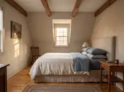 Small bedroom with a leaning fabric headboard set against a matching green accent wall