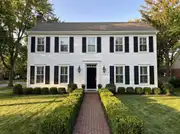 White clapboard colonial with identical black louvered shutters on every window and a black front door