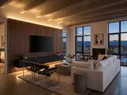 Flat-screen TV on a dark wood-slat accent wall beside a fireplace, with a white sectional and city windows at dusk