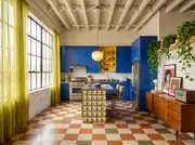 Wide angle of a Dopamine Decor kitchen with bold cobalt blue cabinets, terrazzo tiles, and colorful accents.