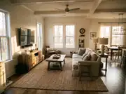 A sofa positioned roughly seven feet from a wall-mounted TV with a rug reaching the front legs