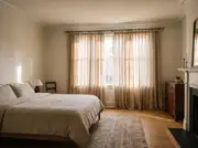 Floor-length linen curtains hung from a rod mounted above and wider than the window, warm afternoon light filtering through