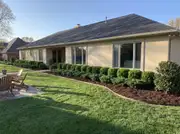 A ranch home's long low facade with trimmed dwarf shrubs kept under two feet along the foundation