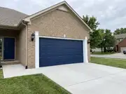 Two-car garage door painted deep navy with white trim, matching the front door on a tan brick house