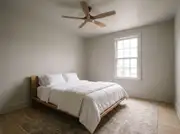 Small bedroom painted the same pale gray on the walls and ceiling with a wood ceiling fan