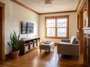 A slim open-shelving media console under a wall-mounted TV, paired with a low ottoman instead of a coffee table