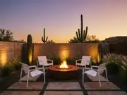 Four white patio chairs around a round fire pit in a desert yard, with tall saguaro cacti and low stone walls behind