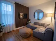 A wood slat panel feature wall behind a mounted TV, with a round mirror on the adjacent wall