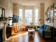 Living room with an off-center TV on a cabinet against the wall, a blue sofa, a desk and chair by three windows
