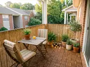 Completed small balcony with wood tiles, a bamboo screen, a wooden bistro table, striped chairs and potted herbs