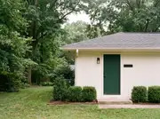 A ranch home entry with a freshly painted deep forest-green front door against white siding