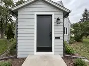 Charcoal door on gray siding with matching matte black handle, kickplate, lantern, mail slot and downspout