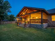 A covered ranch home porch with a half-height stone veneer skirt wrapping the base at dusk