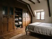 Small attic bedroom with a floor-to-ceiling built-in wardrobe mixing closed doors and open shelves