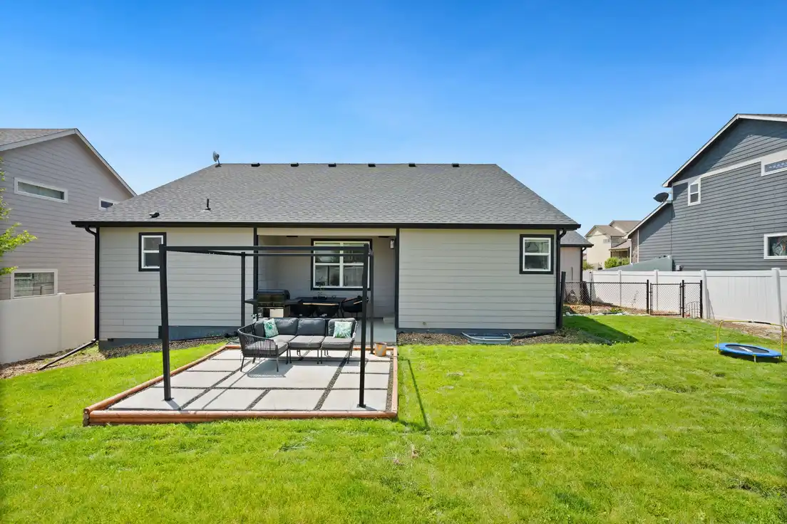 A bare aluminum patio cover kit frame standing freestanding next to a house before roofing