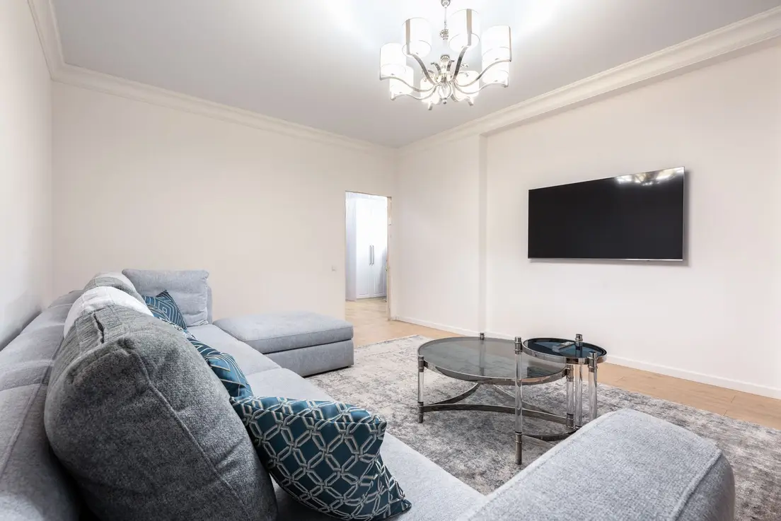 A gray sectional sofa facing a wall-mounted TV in a small living room