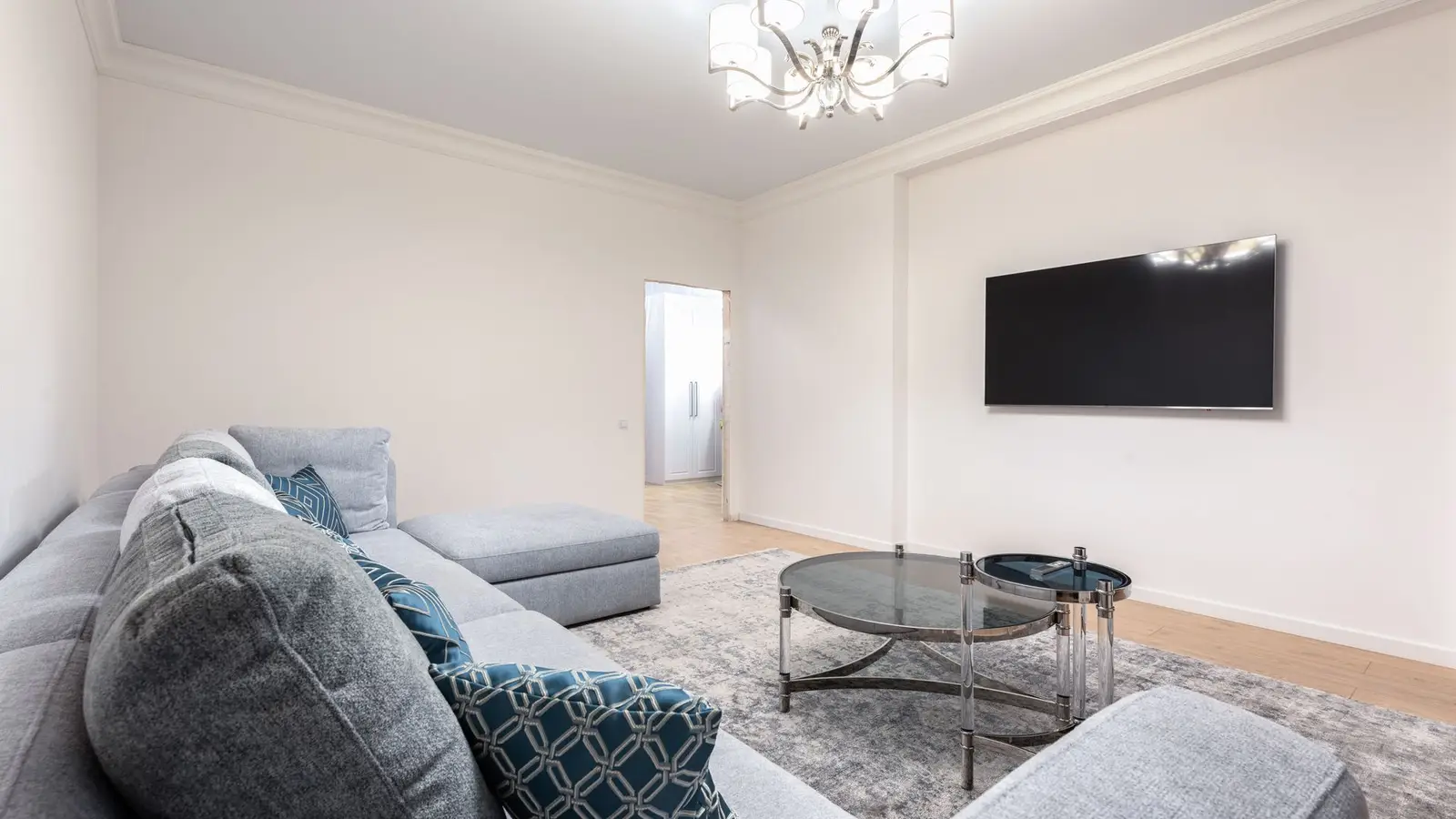 A gray sectional sofa facing a wall-mounted TV in a small living room