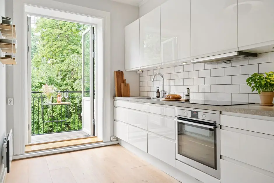 A bright renter-friendly apartment kitchen styled with white cabinets, greenery, and a wood floor