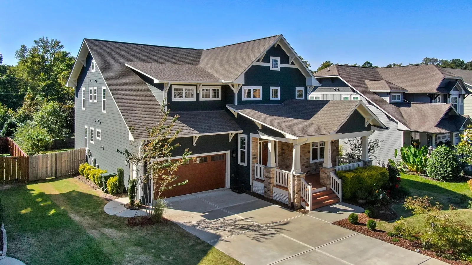 A craftsman-style house with consistent stone base, cedar shake, and dark siding across the facade