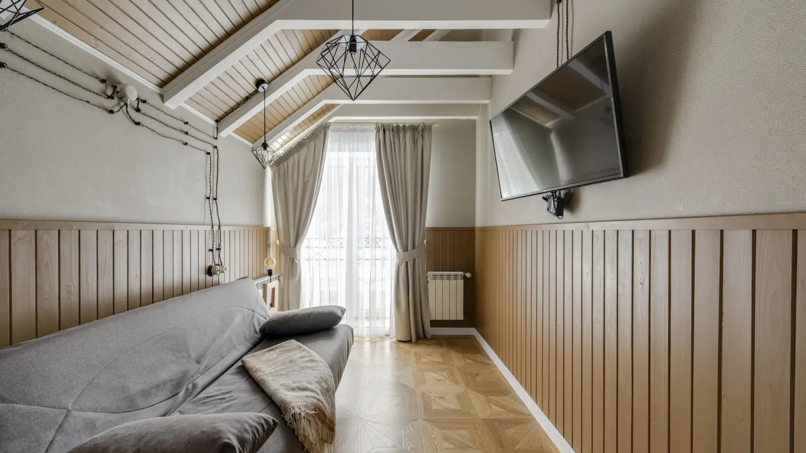 A vaulted wood-paneled ceiling with exposed beams over a living room, an example of farmhouse architectural character