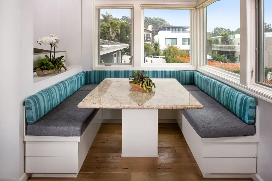 A built-in banquette dining nook with a table in a bright kitchen corner