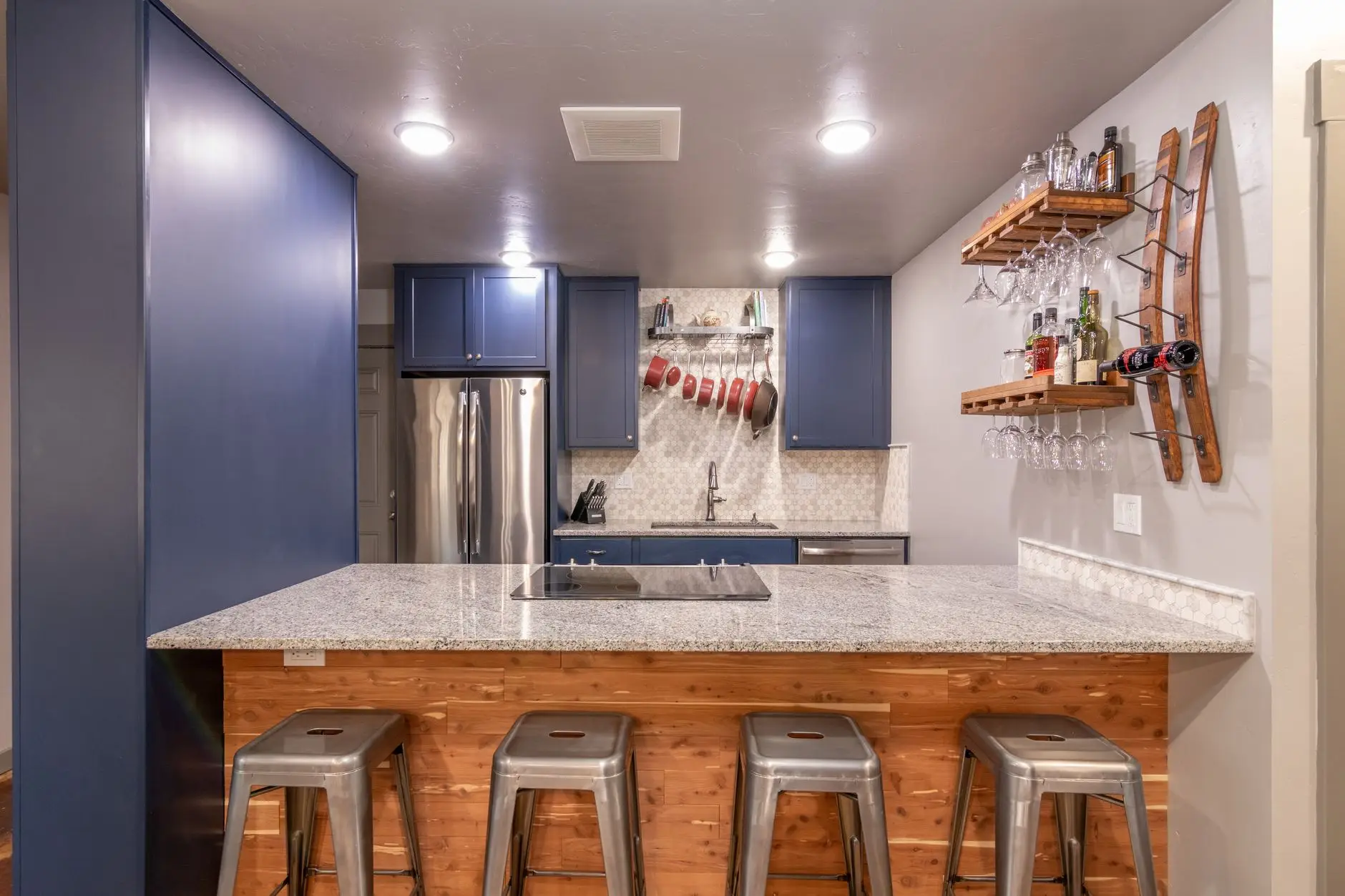 Metal bar stools lined up along a kitchen peninsula with a granite countertop