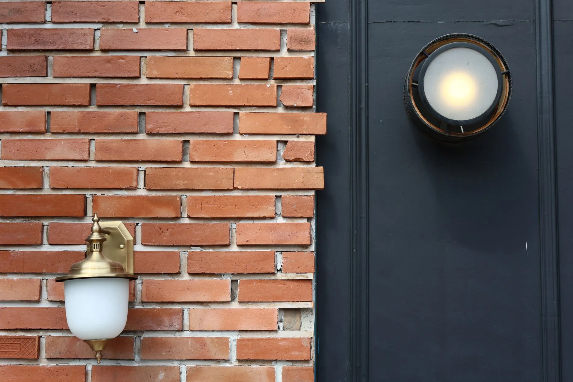 Two mismatched exterior wall light fixtures on a modern farmhouse exterior