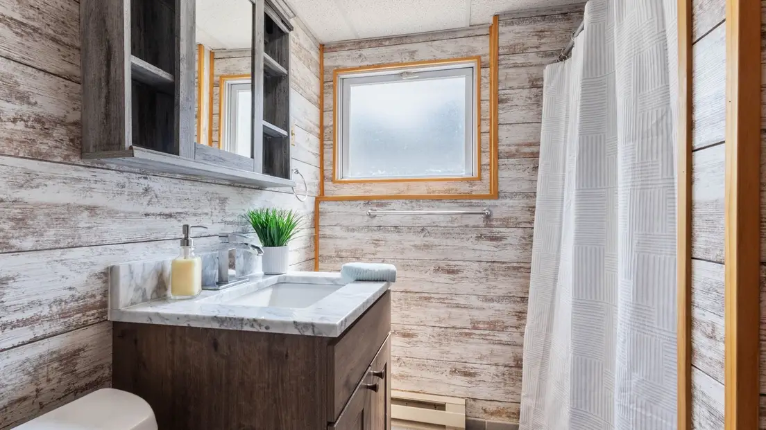 A modern farmhouse bathroom with wood-paneled walls and a dark wood vanity