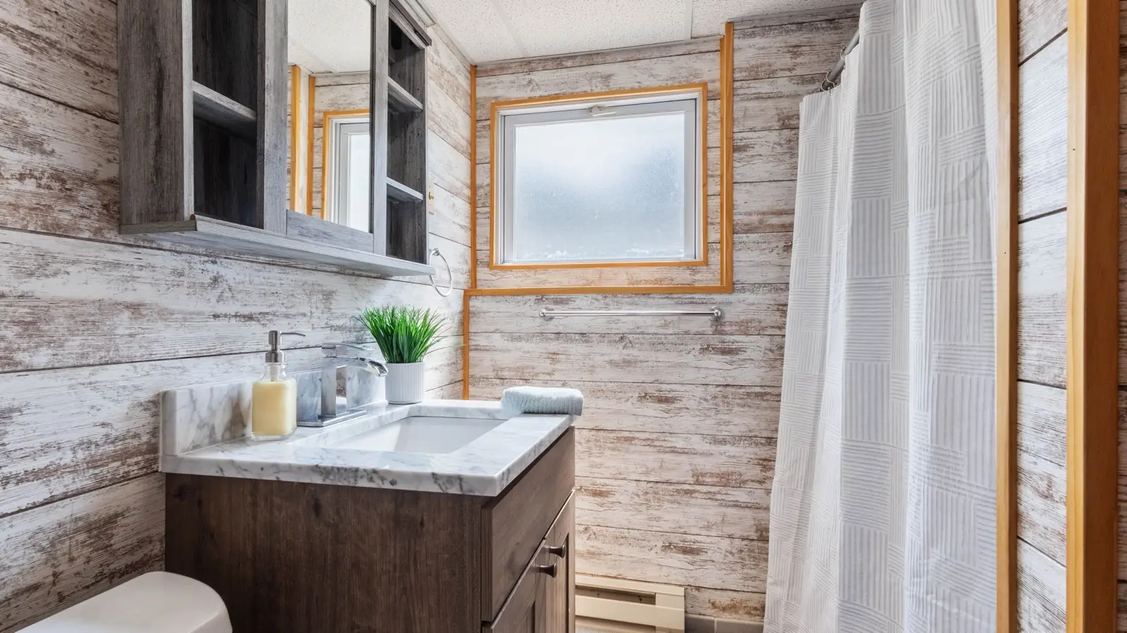 A modern farmhouse bathroom with wood-paneled walls and a dark wood vanity