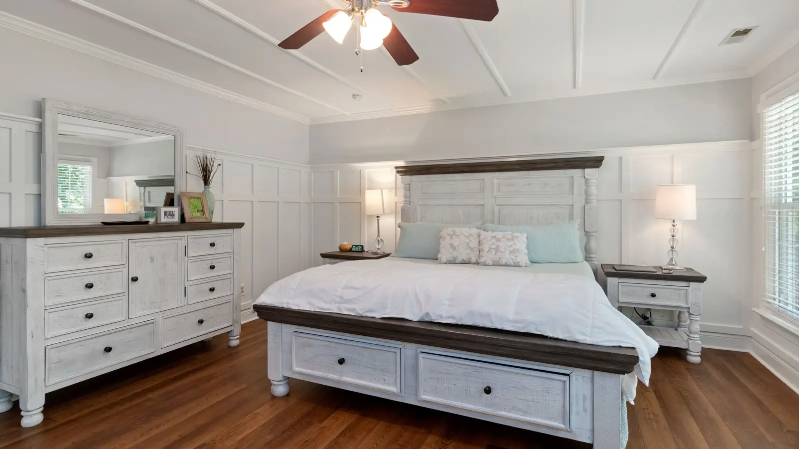 A modern farmhouse bedroom with a whitewashed wood bed frame and matching dresser