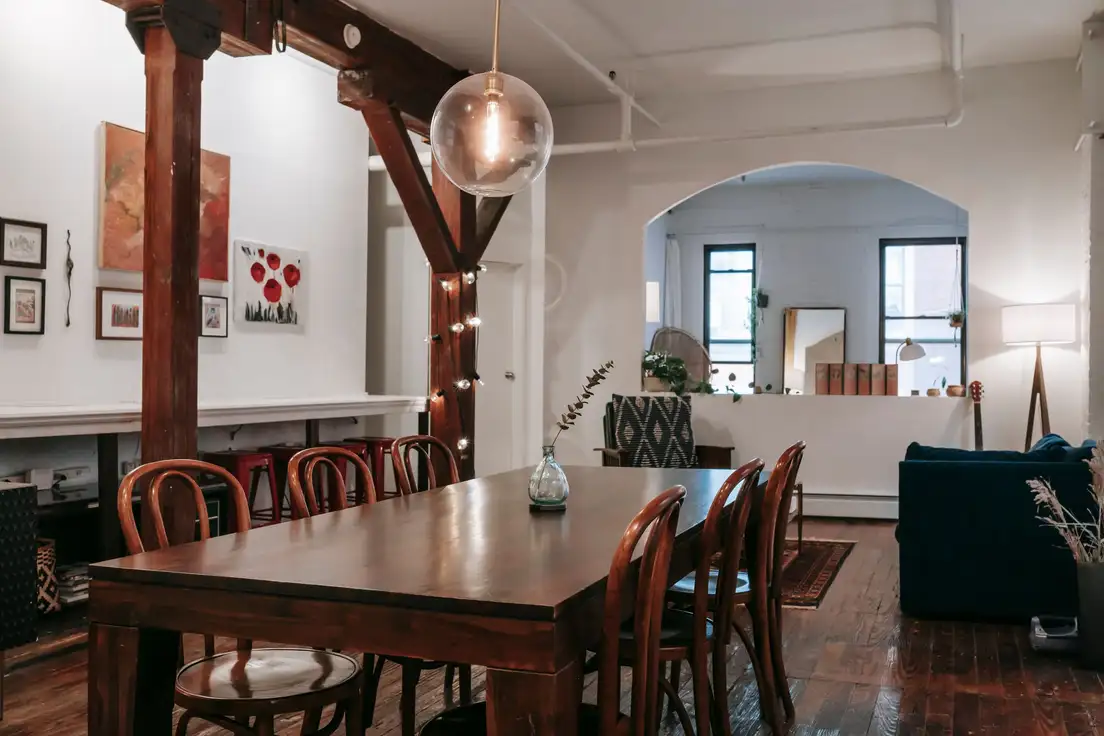 Bentwood dining chairs around a dark wood dining table, with the living area and sofa beyond in an open plan loft