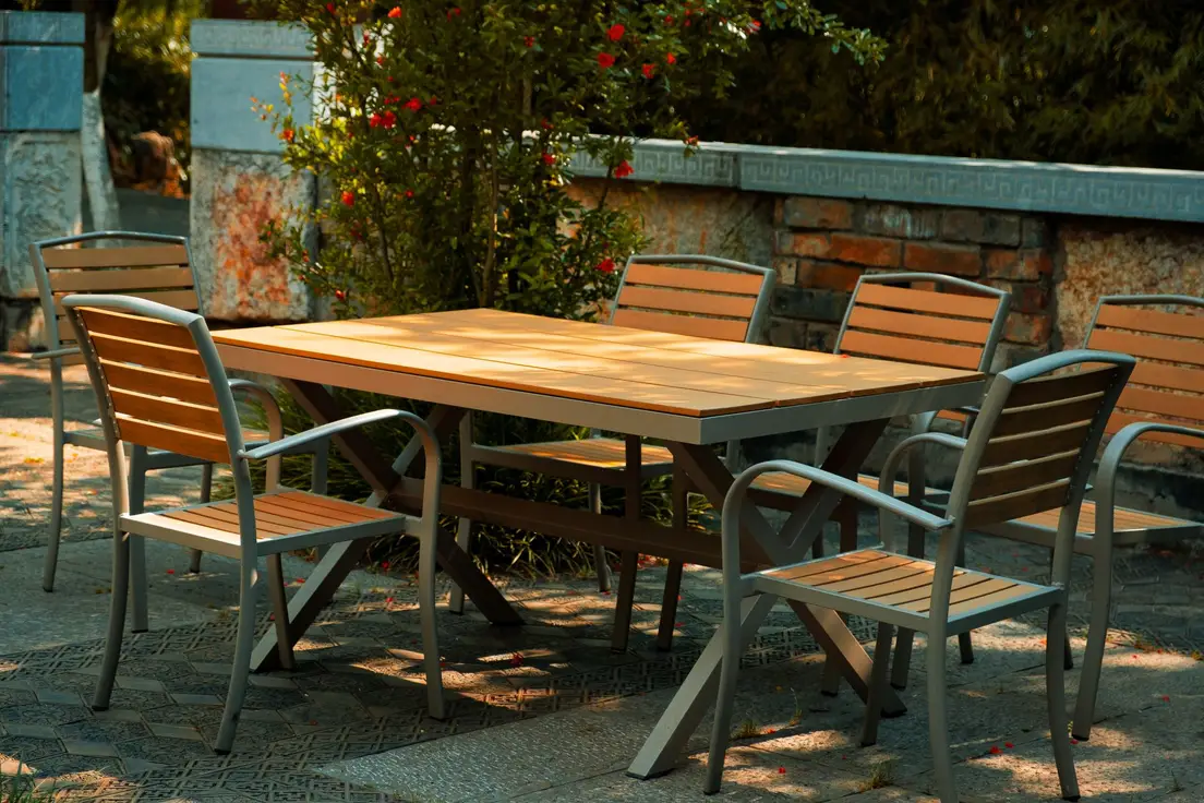 Outdoor dining set on a patterned paver patio framed by a low stone wall