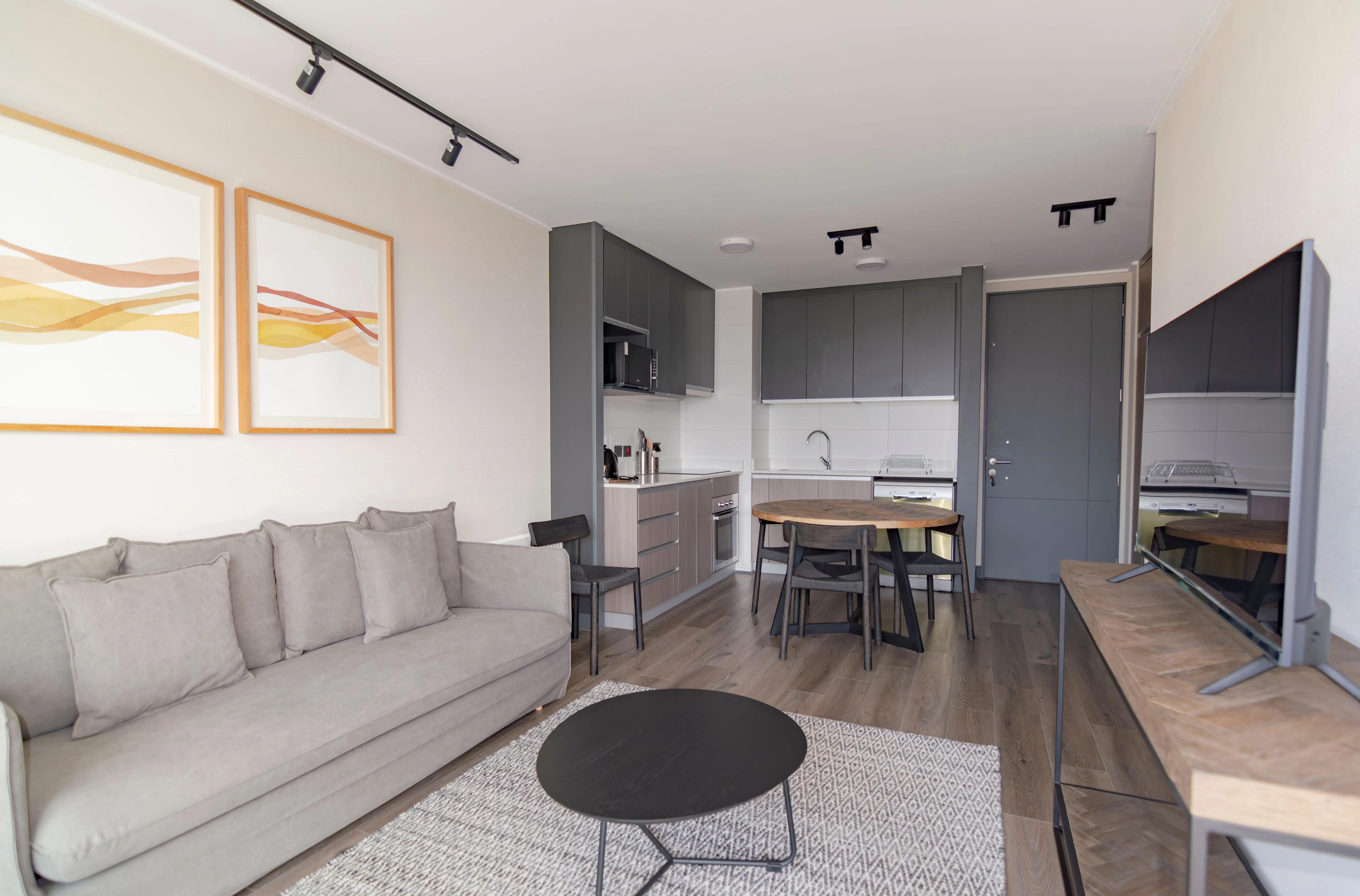 A small modern living room with a gray sofa and neutral decor done on a modest budget