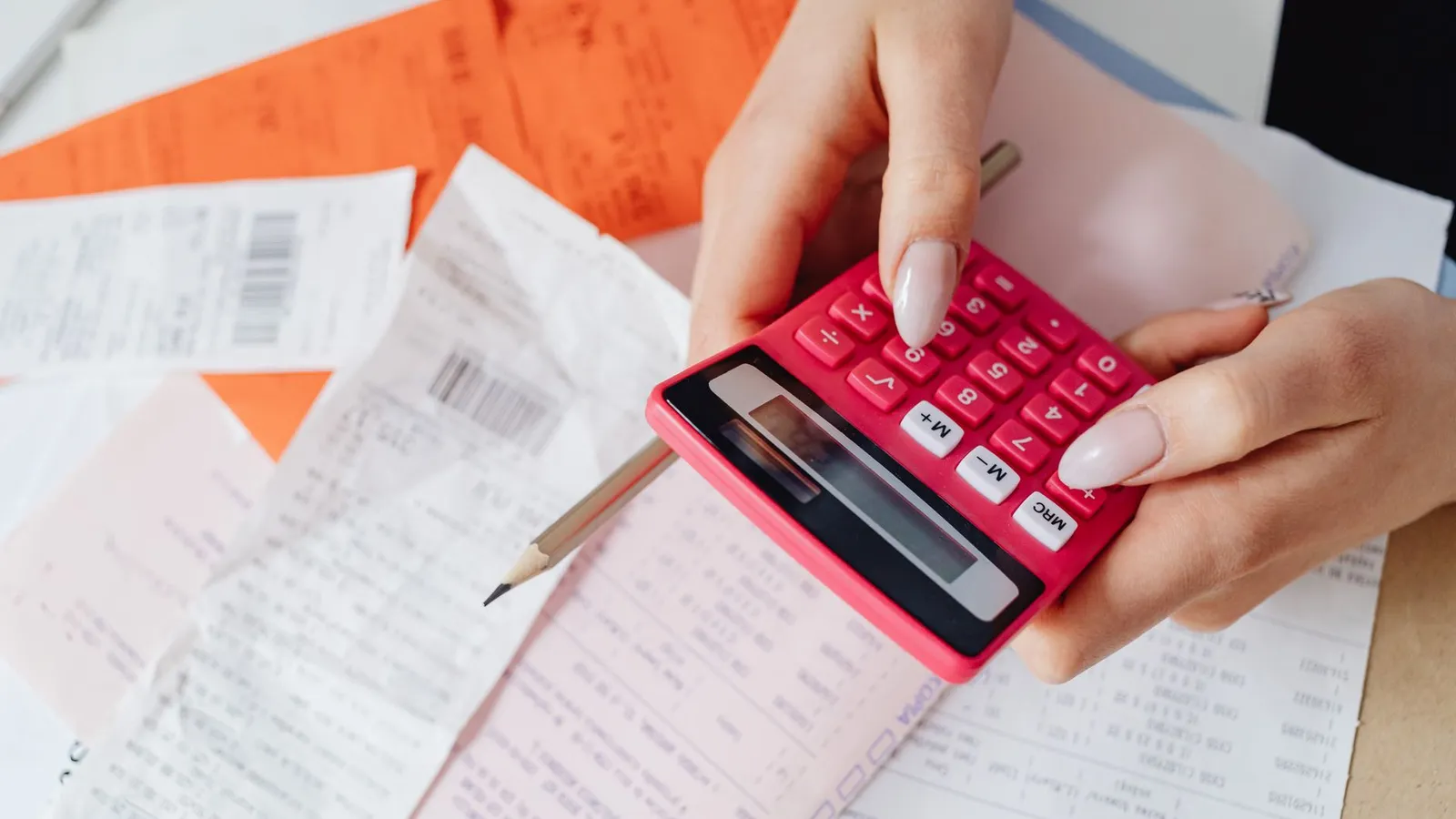 A person using a calculator with receipts to add up a home exterior budget