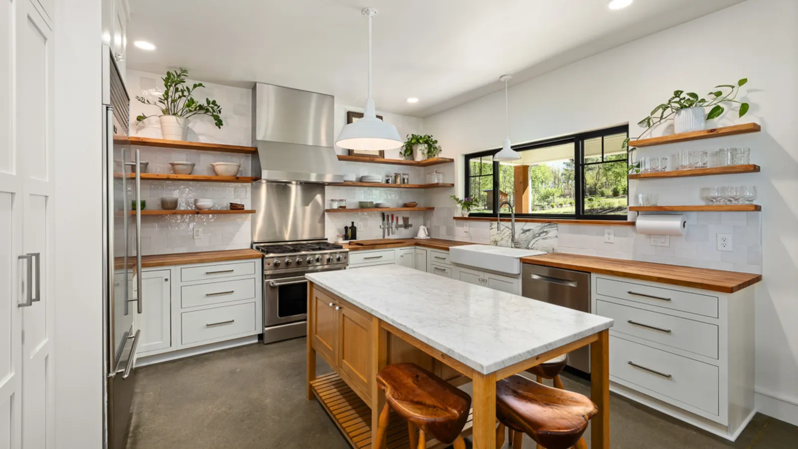 A modern farmhouse kitchen island with a light butcher block-style countertop and wood barstools