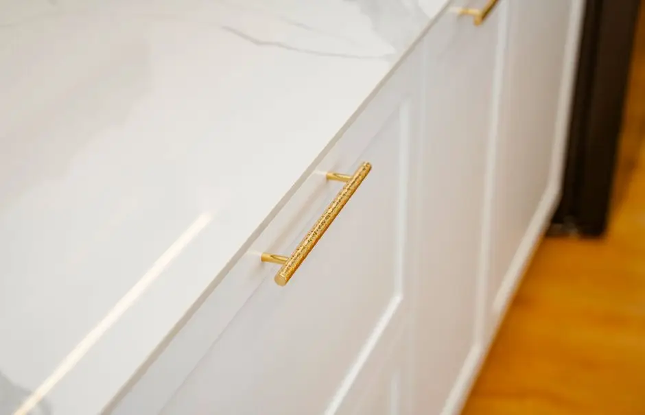 New brass cabinet hardware pulls installed on white kitchen cabinet drawers