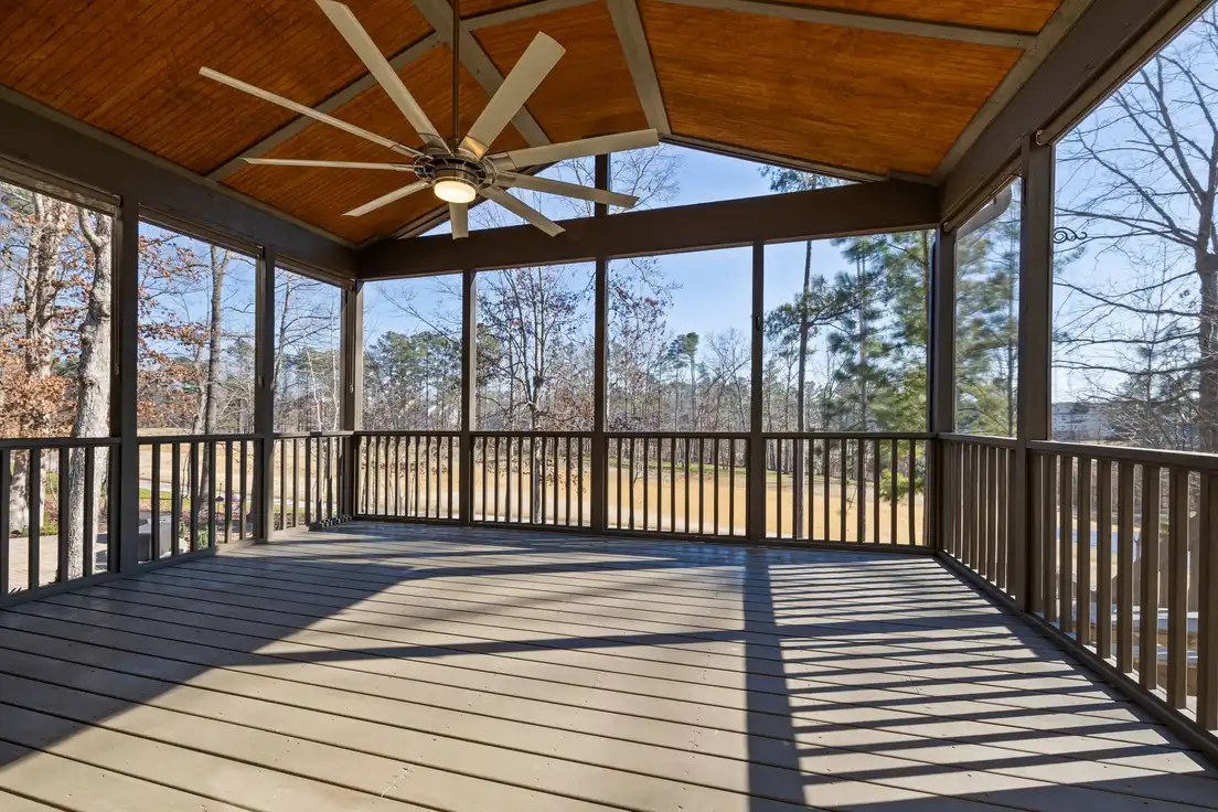 A large wood ceiling fan mounted on the vaulted wood ceiling of a screened patio