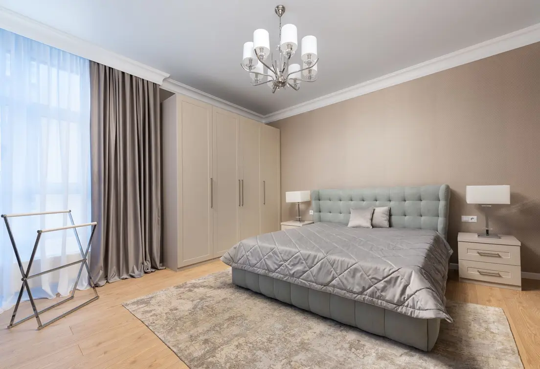 A small primary bedroom with the bed centered on the room's longest wall between two nightstands